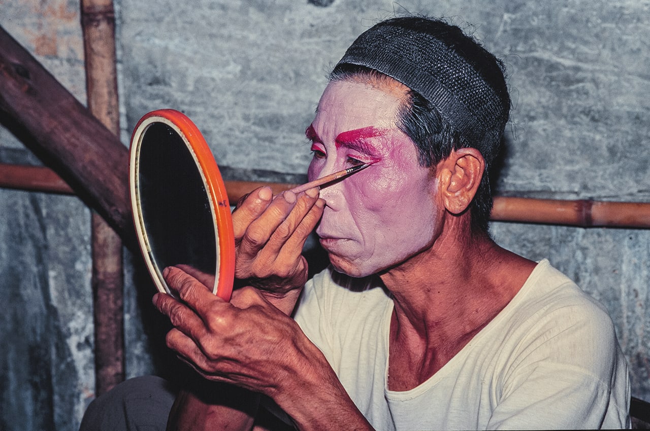 A man paints his face backstage in preparation for a Chinese Opera performance.