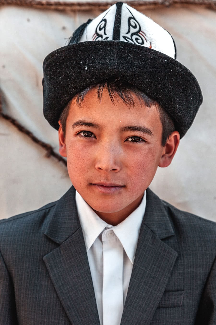 A Kyrgyz boy wearing a traditional Kalpak hat in the Suusamyr Valley.