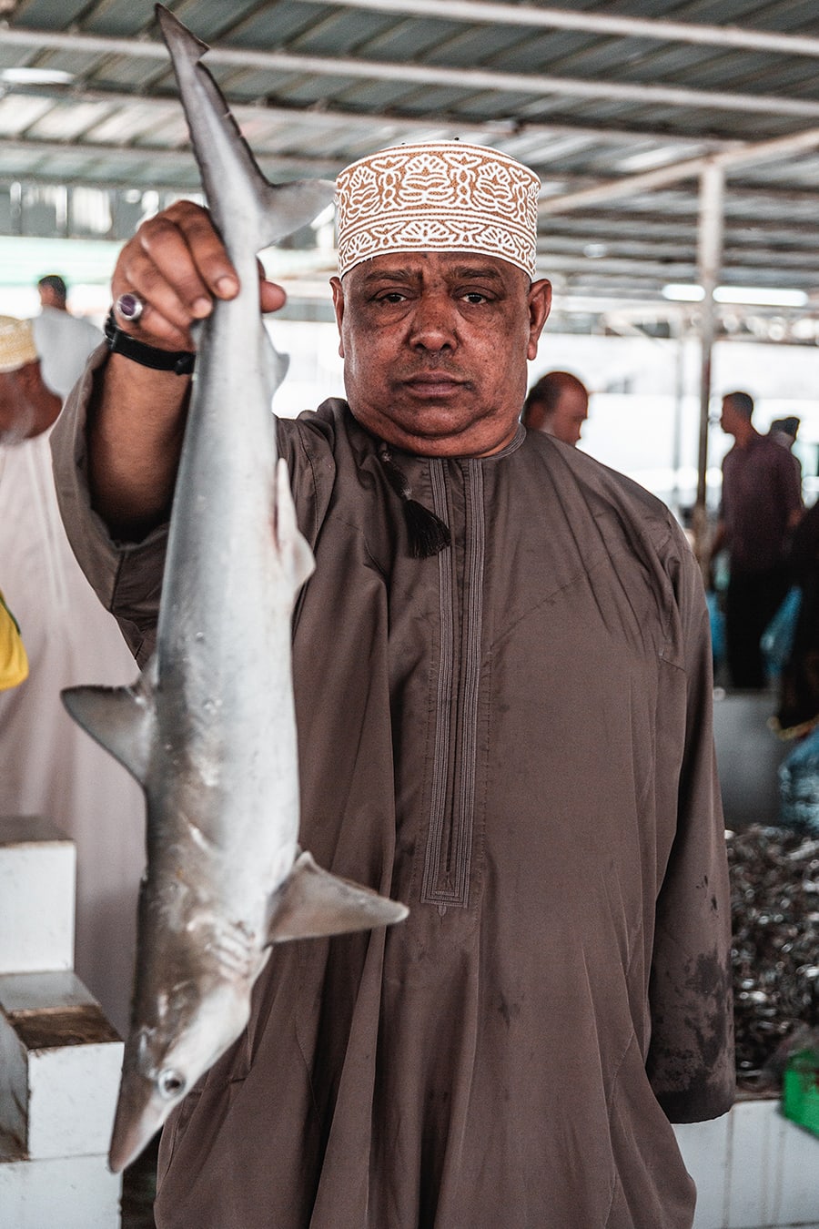 A vendor holds up a shark at the fish market in Sur, Oman.