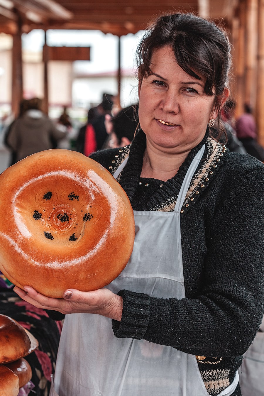 A bread vendor at the Samarkand market proudly shows her wares.